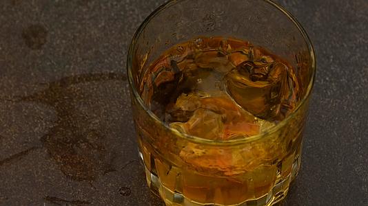 冰落在酒吧柜台的威士忌杯里视频的预览图