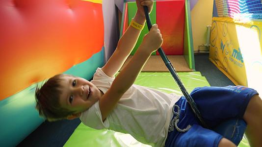 快乐微笑的男孩在儿童室内娱乐中心骑着滑绳快乐的孩子在儿童室内娱乐中心视频的预览图