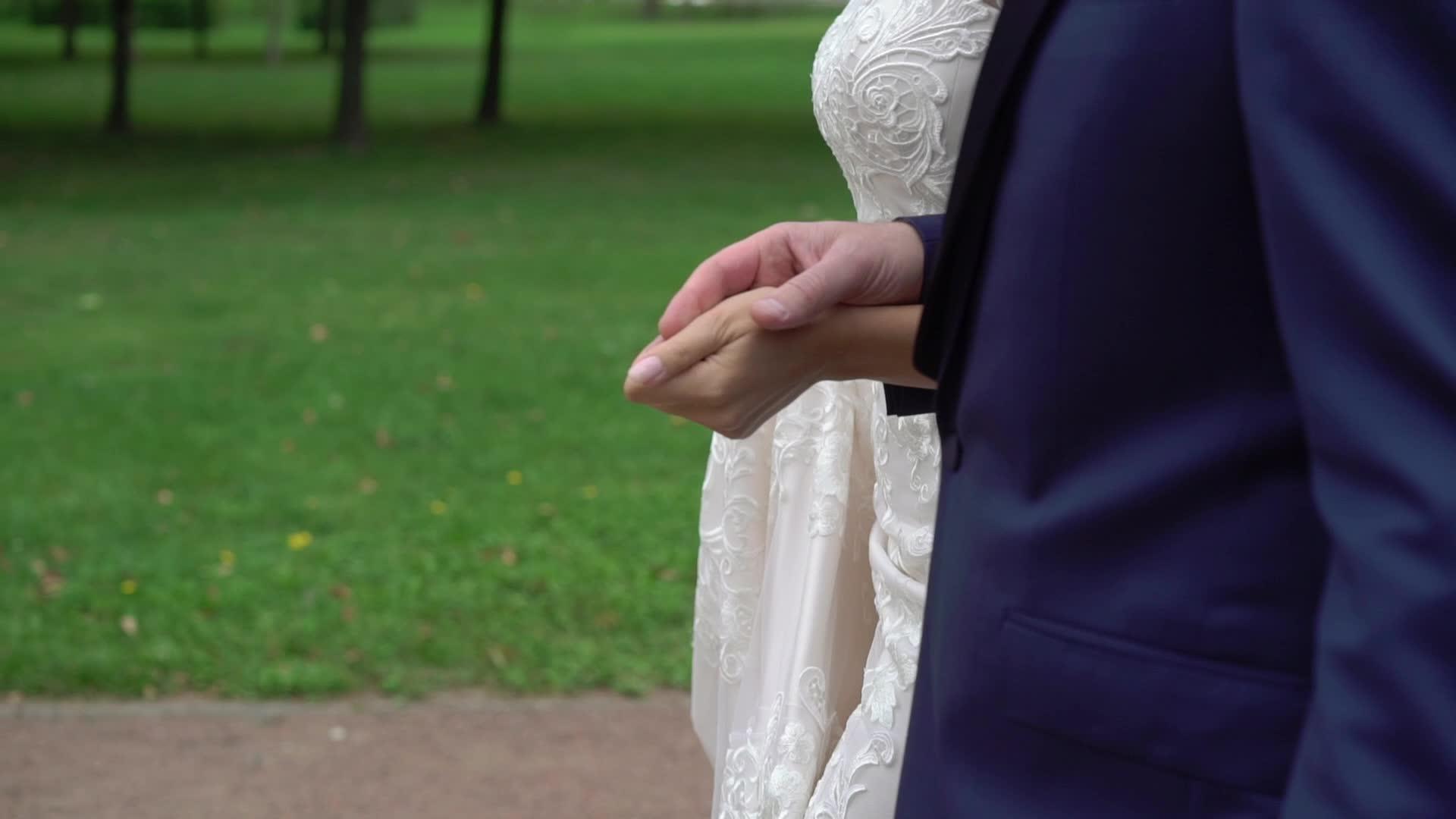 新娘和新郎手牵手在公园里散步视频的预览图