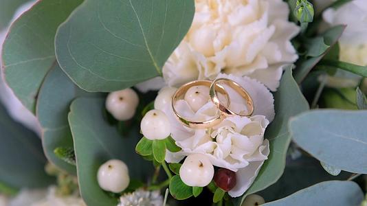 结婚戒指躺在婚礼的花束上视频的预览图