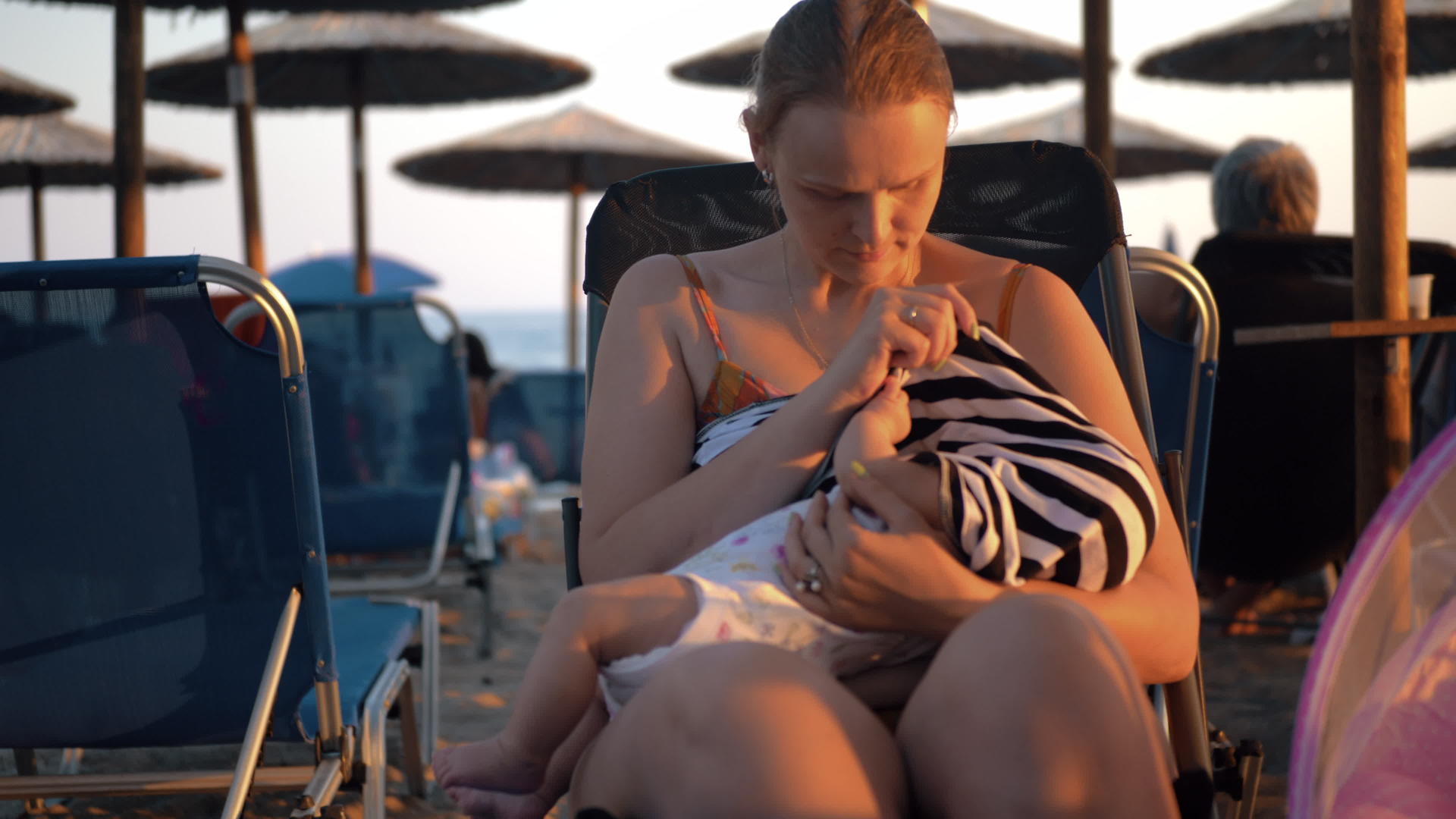 妇女在海滩上哺乳婴儿视频的预览图