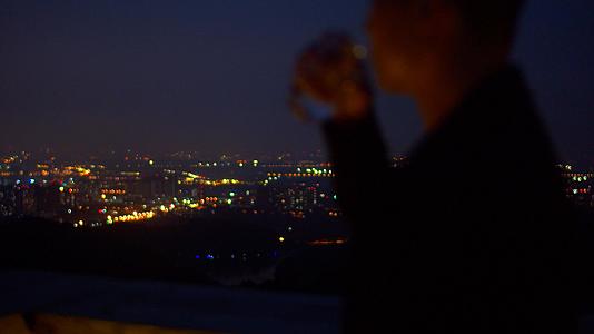4K实拍孤单男子看夜景喝水视频素材视频的预览图