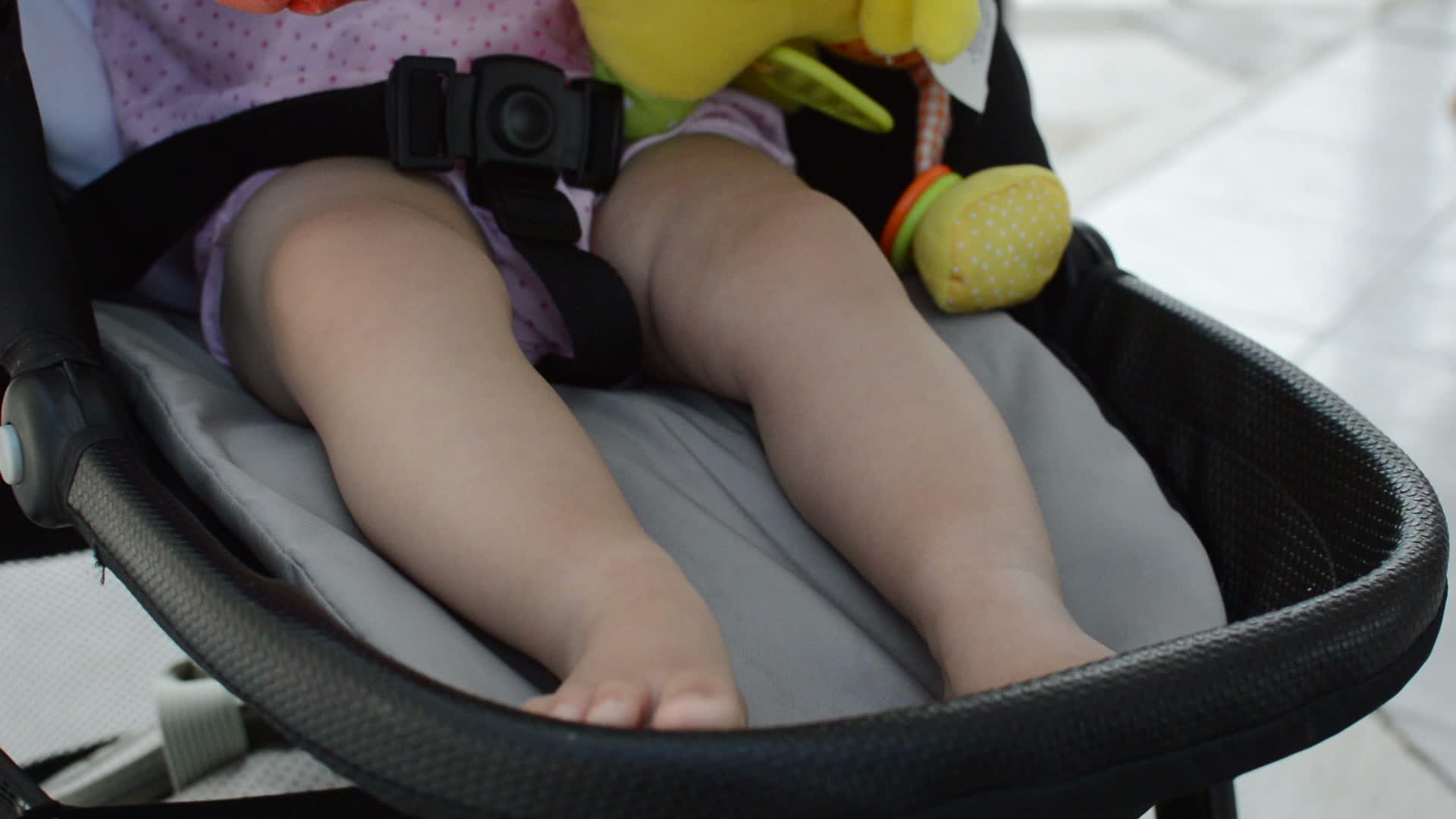 在婴儿马车里玩的时候紧紧地绑着婴儿的腿视频的预览图