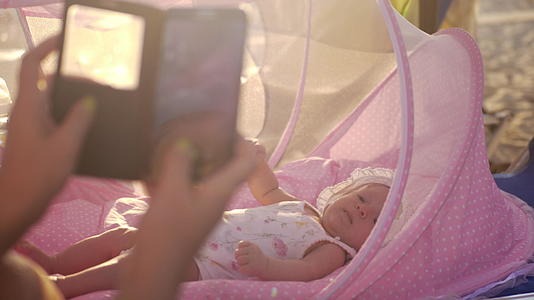 贝斯尼特的母亲在户外拍摄婴儿的手机照片视频的预览图
