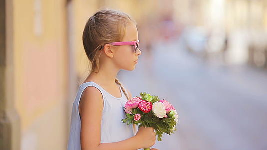可爱的小女孩带着花束在欧佩安城户外散步视频的预览图