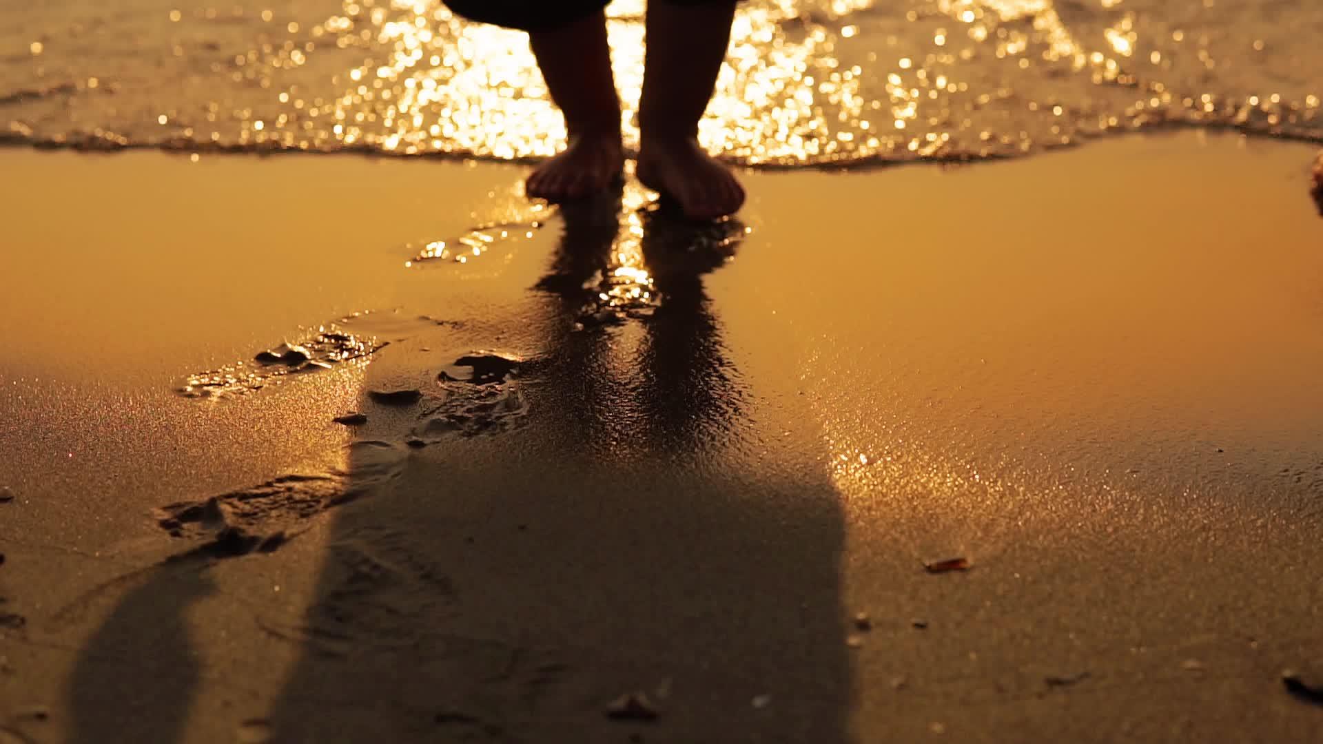 婴儿赤脚在海滩上散步在海滩上冲洗沙子慢慢运动视频的预览图