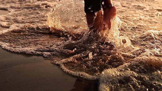 婴儿脚在海滩上行走的电影拍摄在日落时以缓慢的速度冲浪视频的预览图