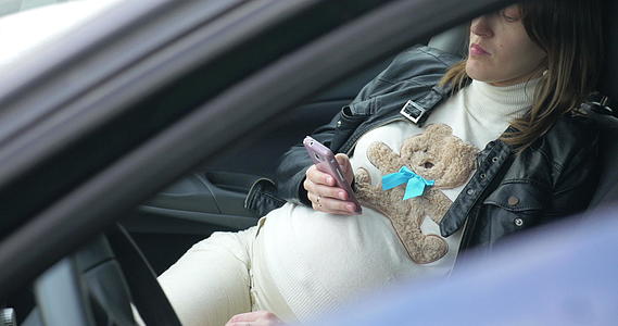 孕妇在车内使用智能手机视频的预览图