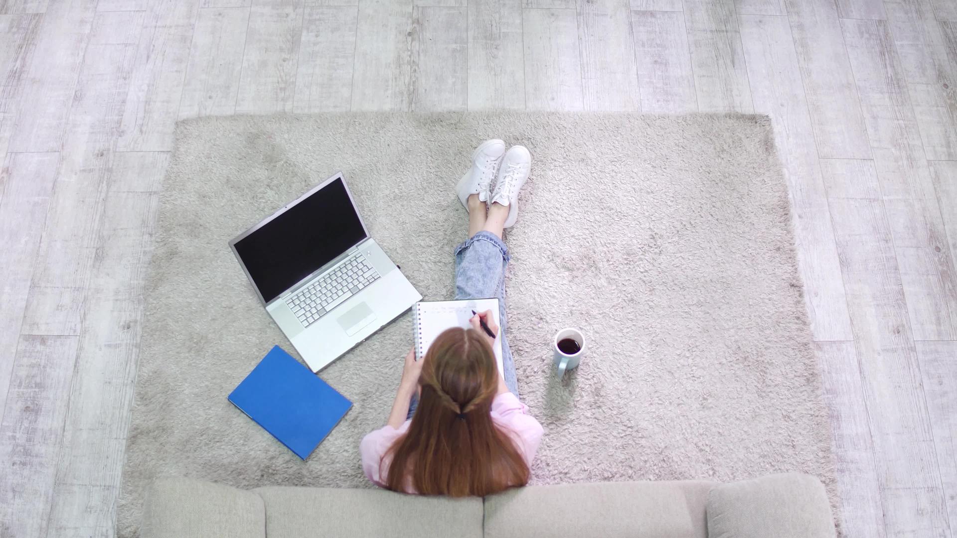 坐在地毯上写笔记本的女孩视频的预览图
