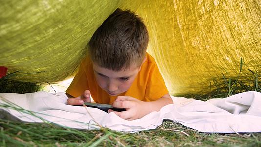 孩子们在移动户外阅读电子书在公园花园里带着小玩意儿童视频的预览图
