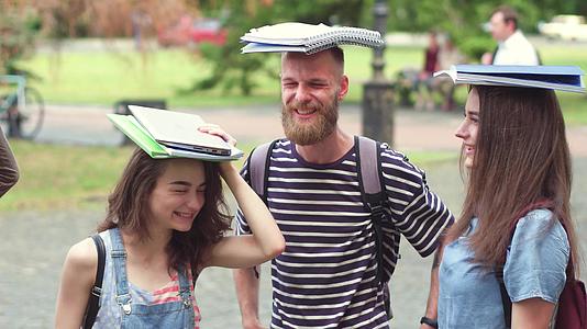 大学生朋友站朋友拿着头上的书的印象视频的预览图