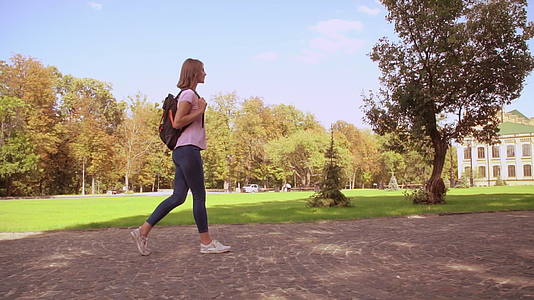 快乐的女人带着背包在校园里走来走去视频的预览图