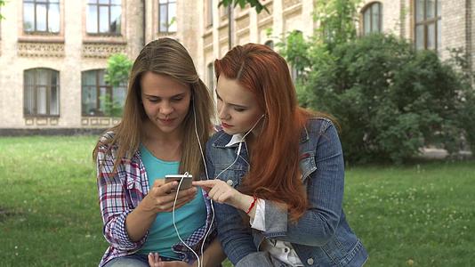 女学生在校园里用智能手机听音乐视频的预览图
