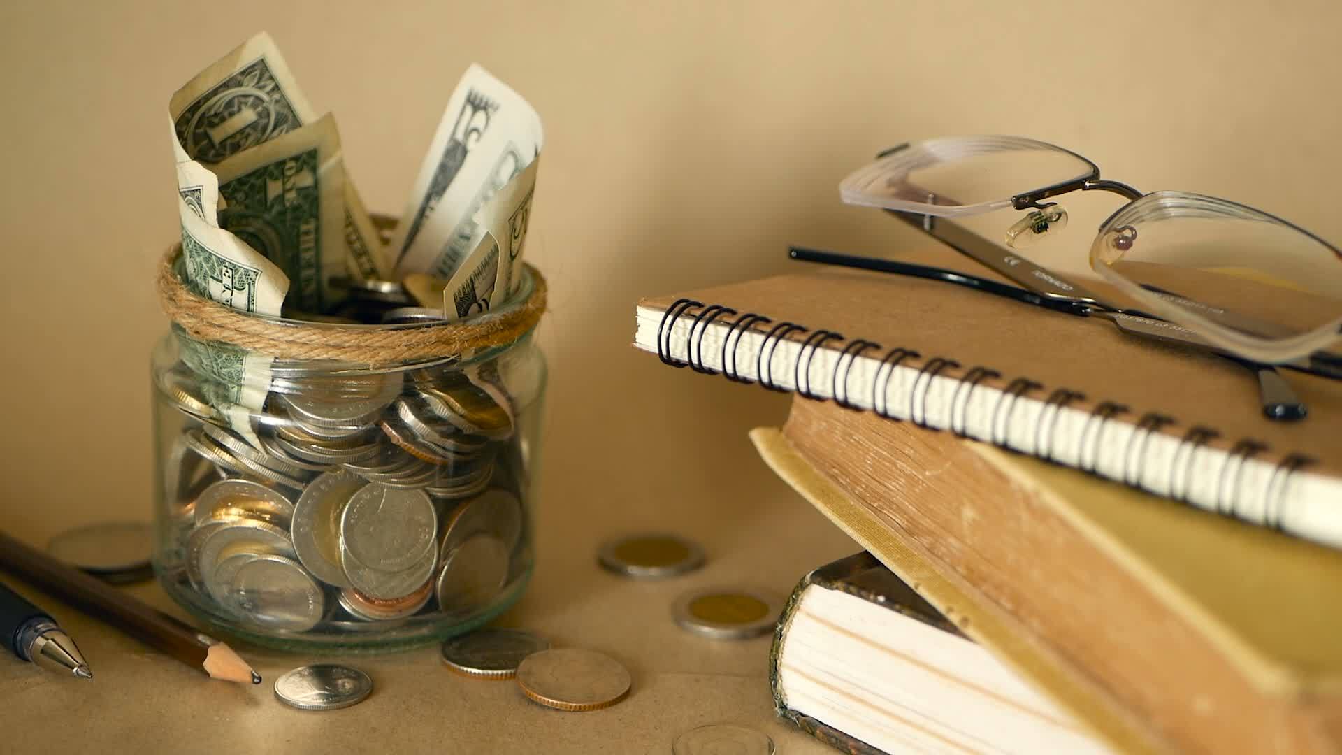 书籍、学费或教育融资 里面藏着装满硬币和钞票的玻璃便士罐视频的预览图