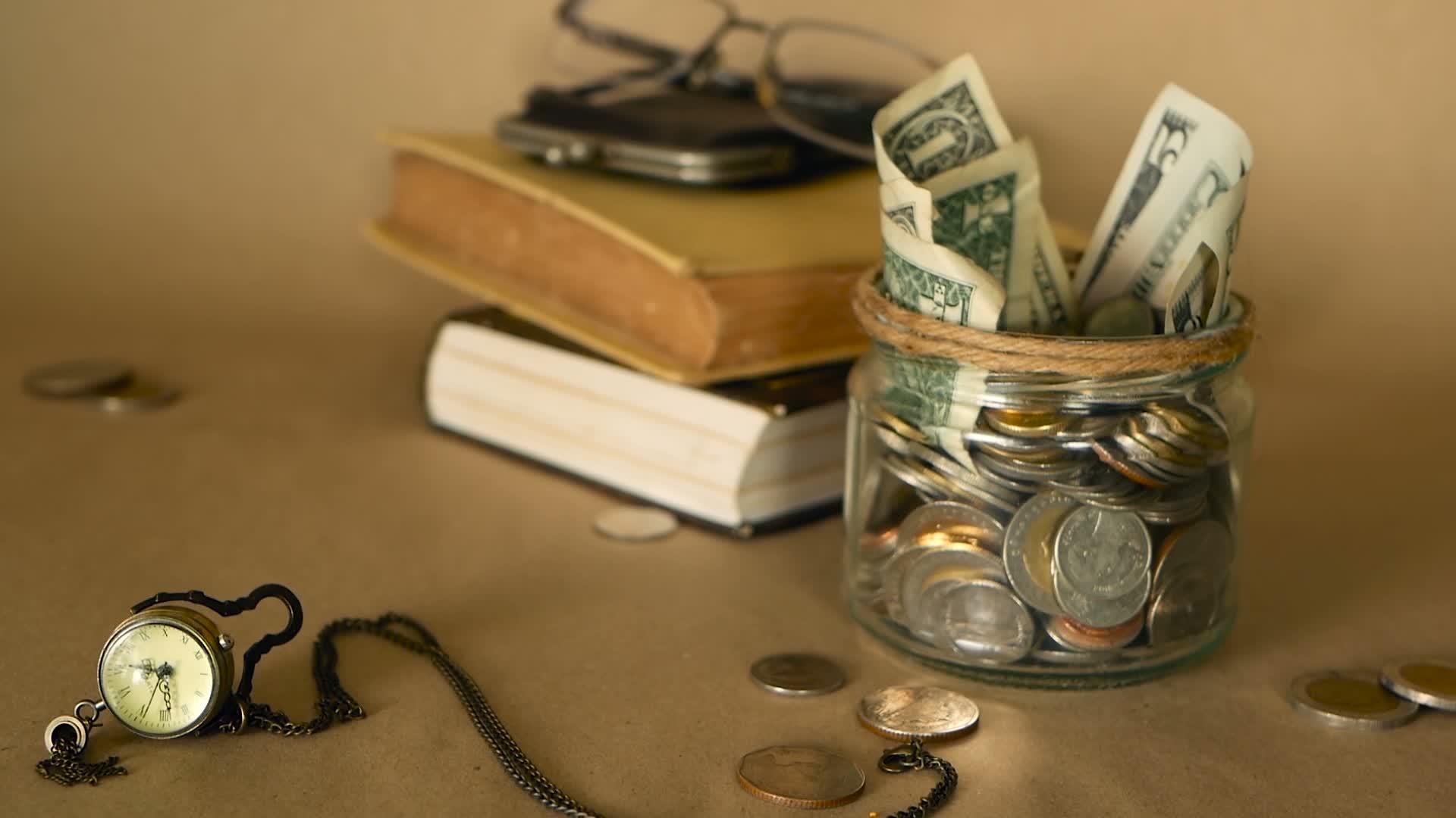 书籍、学费或教育融资里面藏着装满硬币和钞票的玻璃便士罐视频的预览图