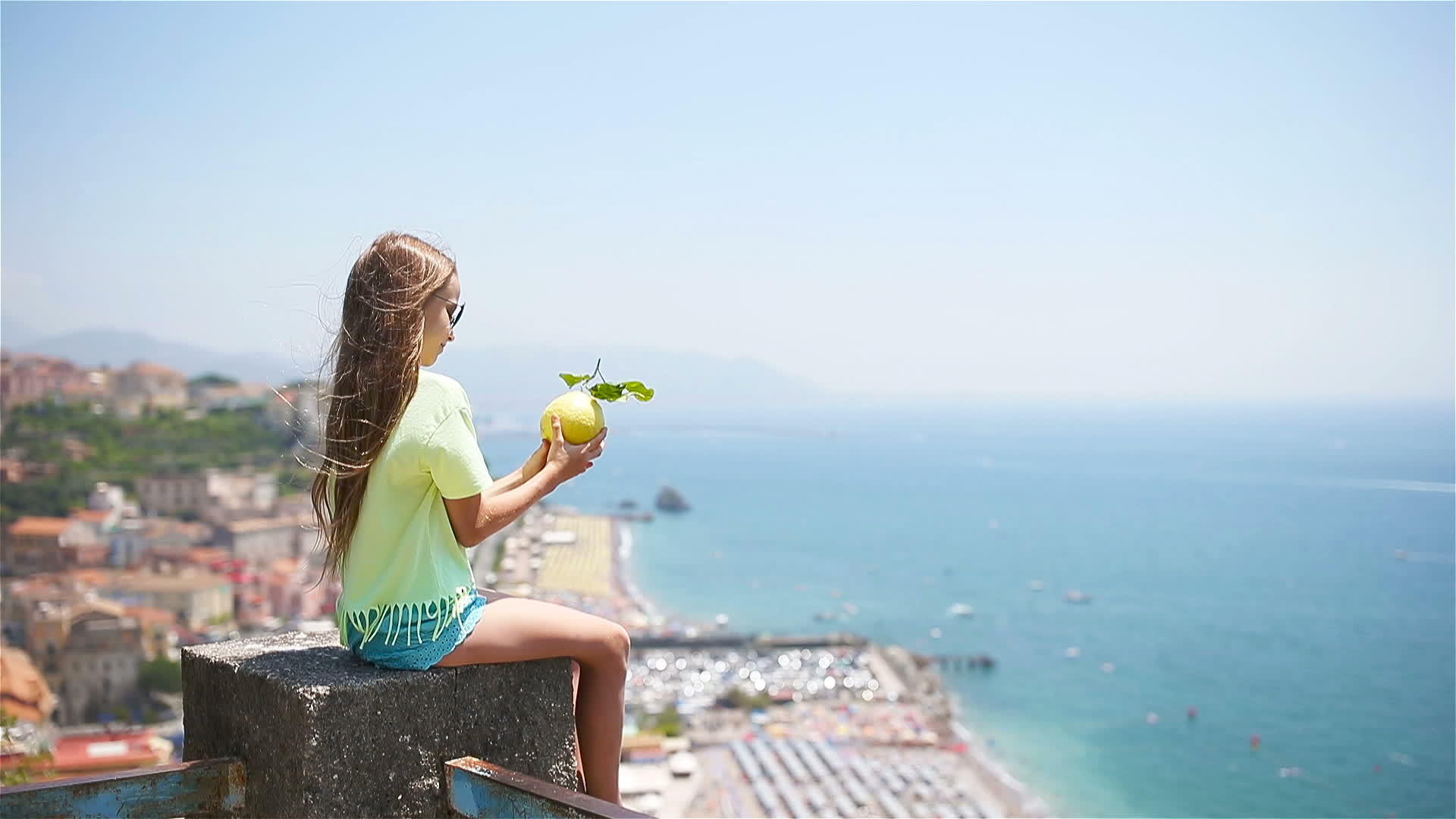 在地中海和天空的背景下手里拿着大黄柠檬视频的预览图