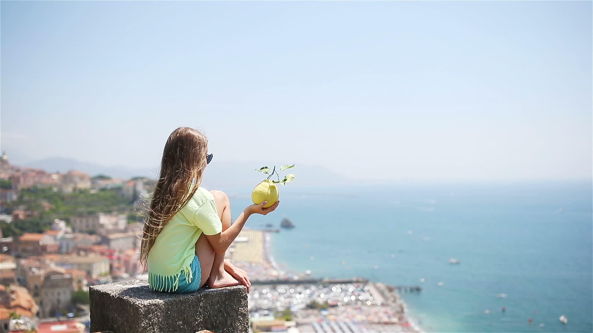 在地中海和天空的背景下手里拿着大柠檬视频的预览图