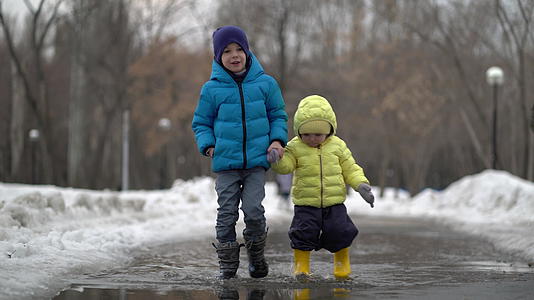 冬天男孩和女孩在水坑里行走视频的预览图