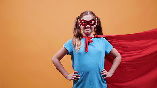 超级英雄的年轻女孩在她的眼睛上戴着红色斗篷和面具视频的预览图