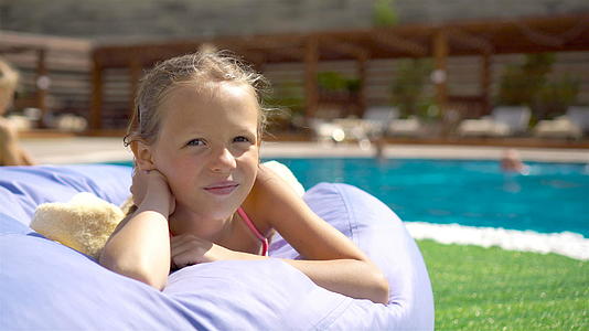 美丽的小女孩在户外游泳池附近玩得很开心视频的预览图