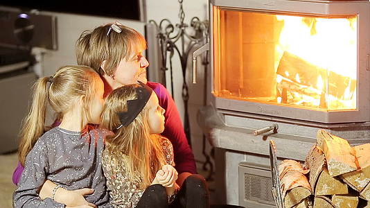 她的祖母和两个小孙女坐在一个壁炉旁边在他们家里视频的预览图