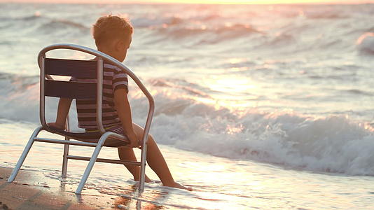 男孩独自坐在椅子上坐在大海上视频的预览图