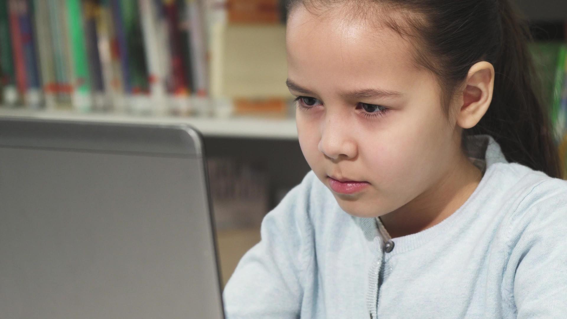 可爱的小女孩专注于笔记本电脑视频的预览图
