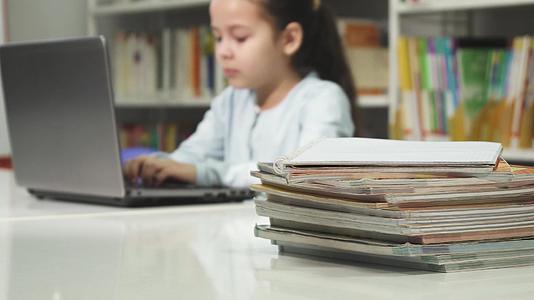 一个小女孩在学校学习和做作业时使用笔记本电脑视频的预览图