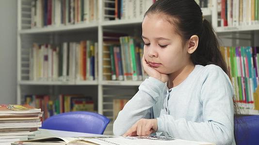 这个可爱的小女孩在图书馆读书时做梦和做梦视频的预览图