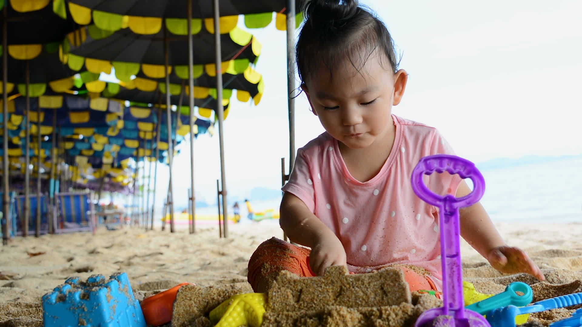可爱的亚洲女婴在海滩上玩玩具视频的预览图