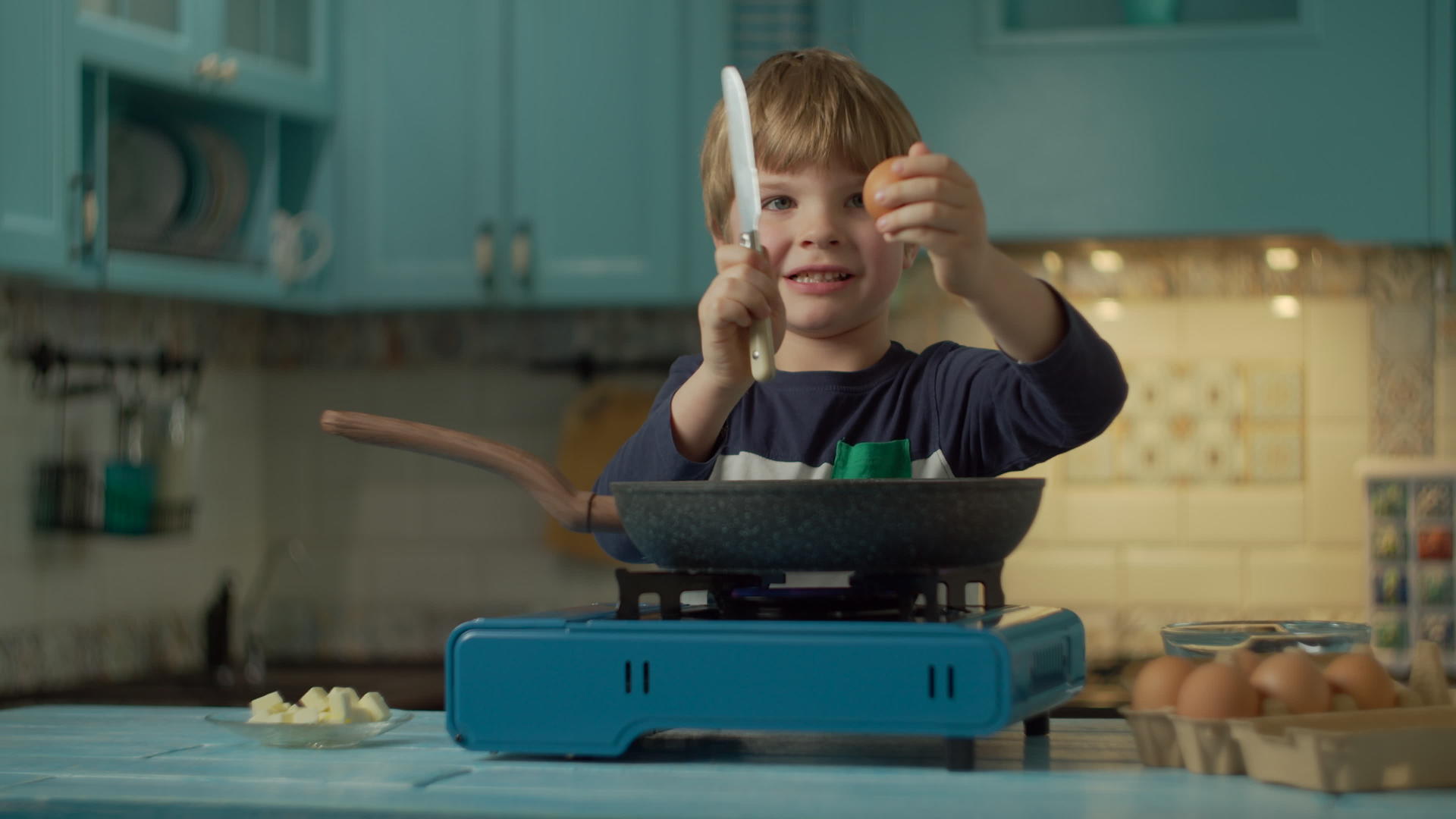 在家里的蓝色厨房里孩子们独自做煎蛋用刀打碎鸡蛋便携式视频的预览图