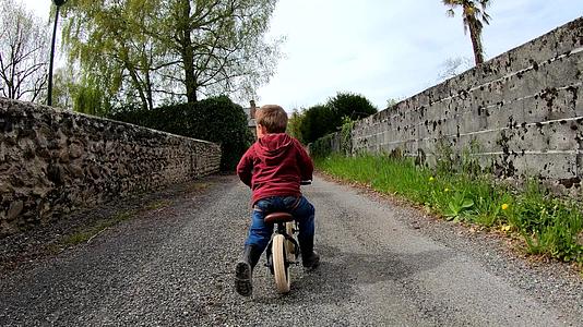 慢动作小男孩骑着平衡的自行车向后仰望着视频的预览图