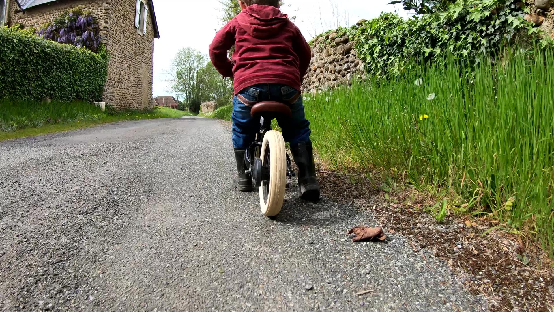 慢动作小男孩骑着平衡的自行车向后仰望着视频的预览图