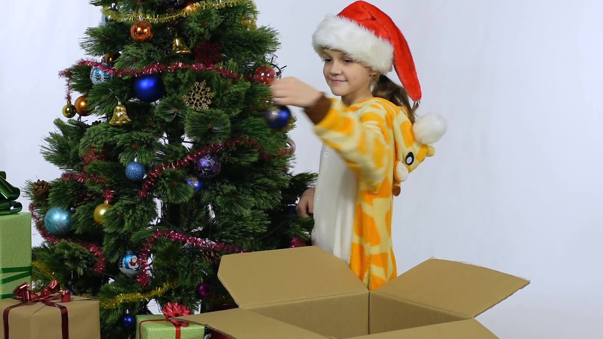 女孩从圣诞树上摘下圣诞装饰品放在盒子里视频的预览图
