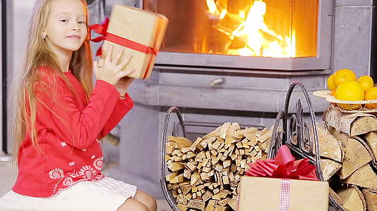 一个好女孩在壁炉附近微笑着送圣诞礼物视频的预览图