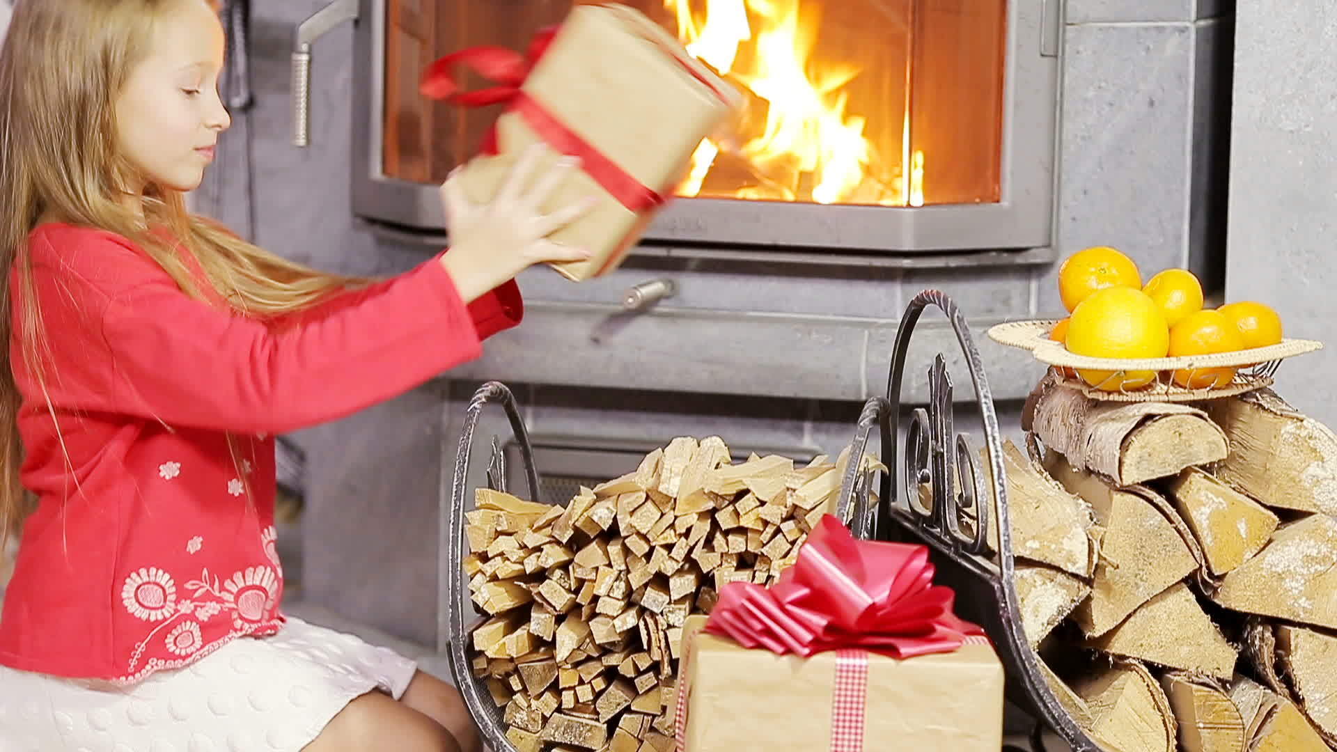 可爱的小女孩在壁炉附近开了一个圣诞礼物视频的预览图