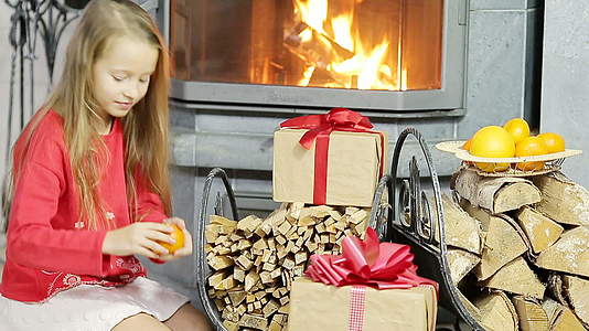快乐的好女孩在壁炉附近打开圣诞礼物视频的预览图