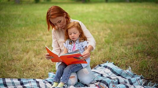 母亲和女儿在公园里读了一本书视频的预览图