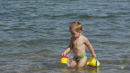 可爱的小男孩在海里玩耍视频的预览图