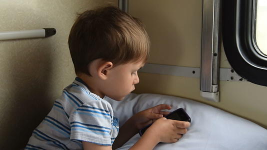 男孩在火车上玩手机游戏视频的预览图