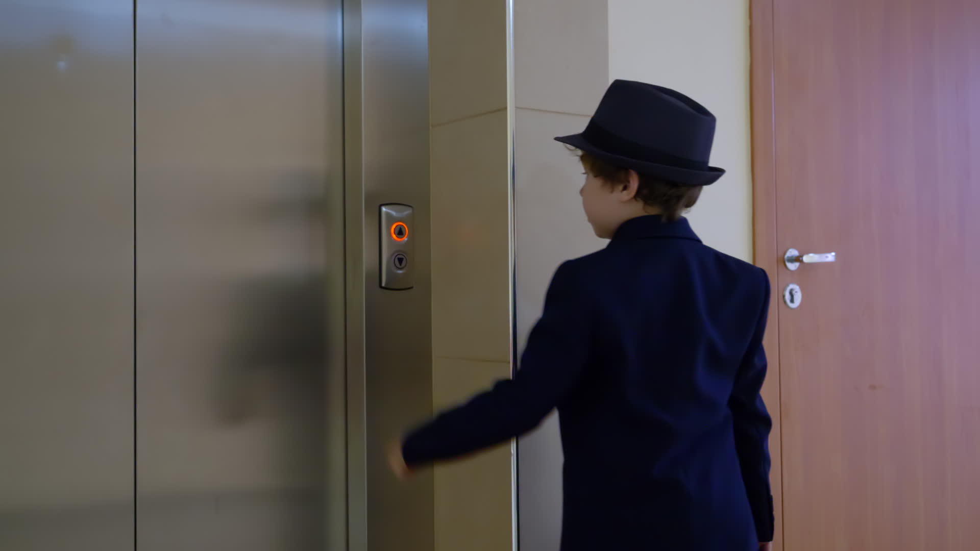这个小男孩看起来像一个穿着西装和帽子的商人在办公室等电梯视频的预览图
