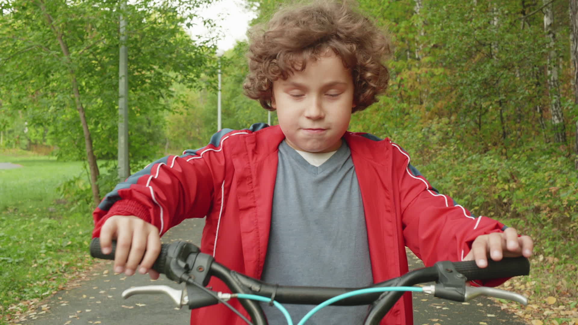 可爱的小男孩在公园里骑自行车视频的预览图