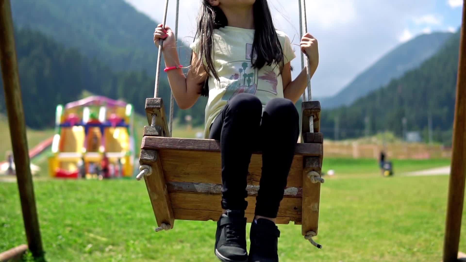 快乐的小女孩在操场上摇摆从低角度慢慢移动电影Dof视频的预览图
