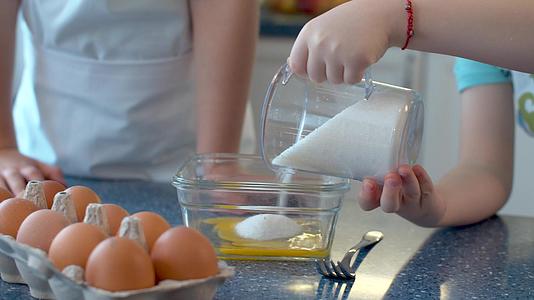 孩子们用手把糖倒进玻璃碗里视频的预览图