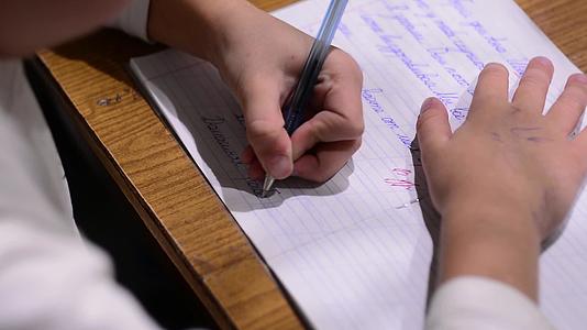一个学龄儿童在笔记本上写道他用左手写道视频的预览图