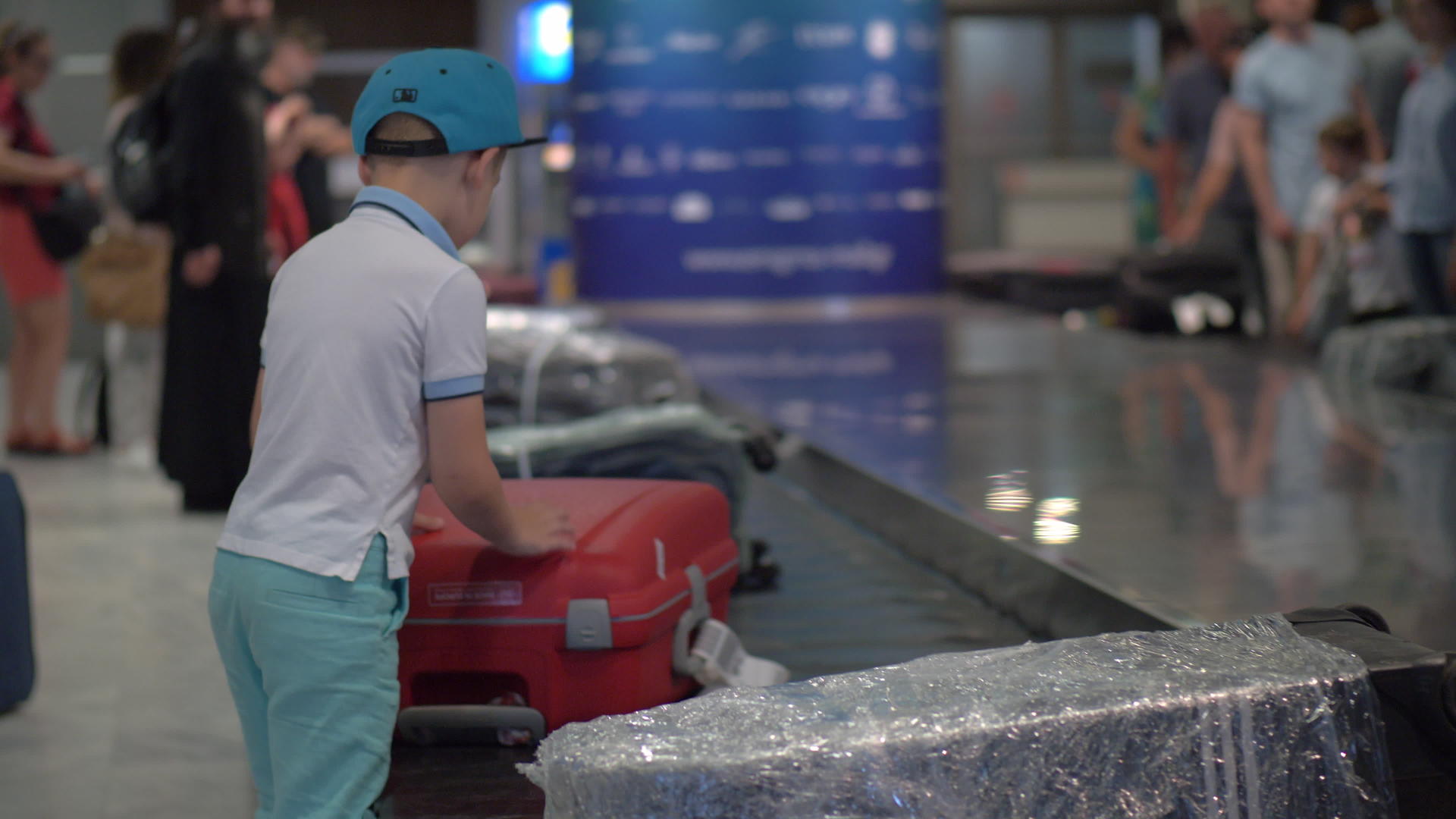 男孩在机场的行李传送带上寻找他的行李箱视频的预览图