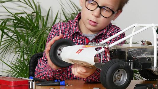 小男孩在家里修理一辆无线电控制车的模型视频的预览图