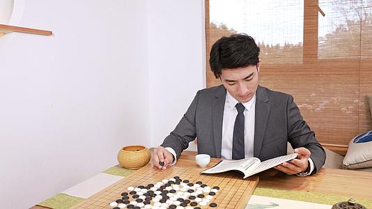 穿西装的男青年边喝茶边围棋书籍视频的预览图