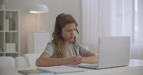 在线儿童通过耳机和笔记本电脑视频聊天在家上学视频的预览图