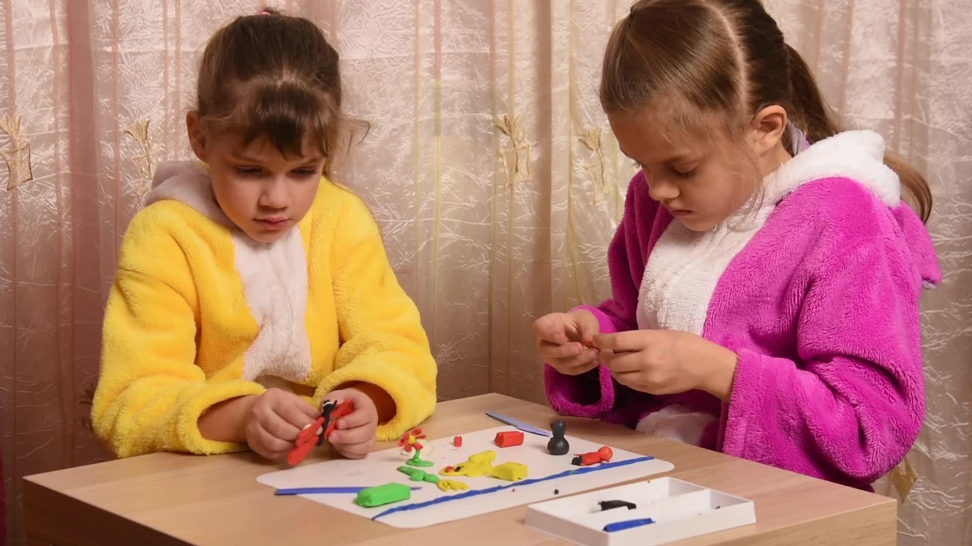 女孩们用坐在桌子旁的塑料制成的装饰品视频的预览图